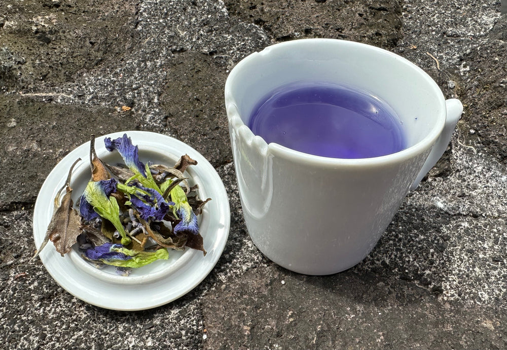 Island Breeze tea in white mug with dried tea product on lava stone wall